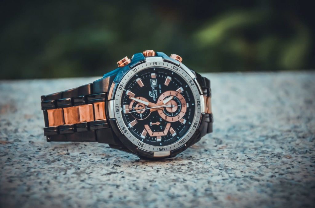 Black and bronze watch placed on stone surface