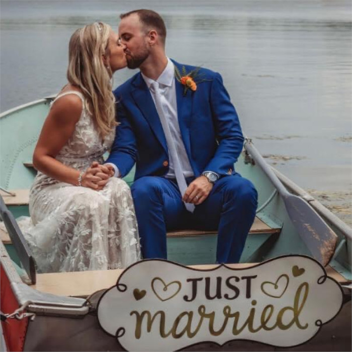 A couple is kissing in a row boat. Sign reads 'just married' 