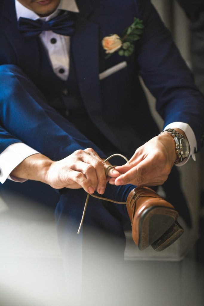 Groom tying dress shoes