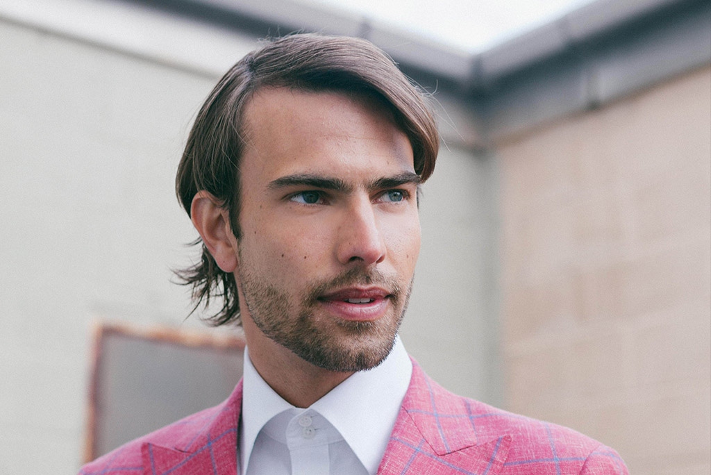 Long hairstyle example. A man wearing pink suit with long hair style that complements his face shape.